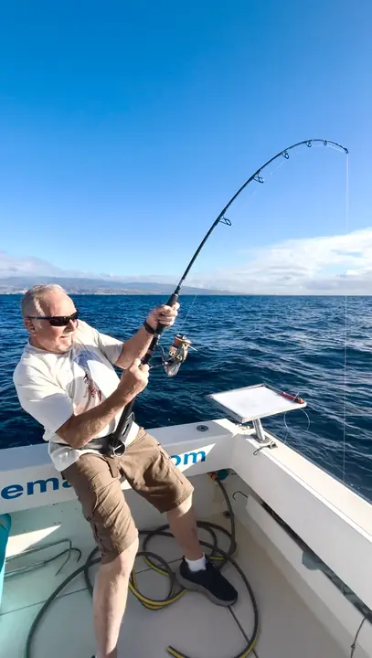 Fiskare som drillar en fisk med spöet böjt till max