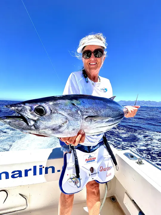 Leende fiskare som håller en tonfisk ombord