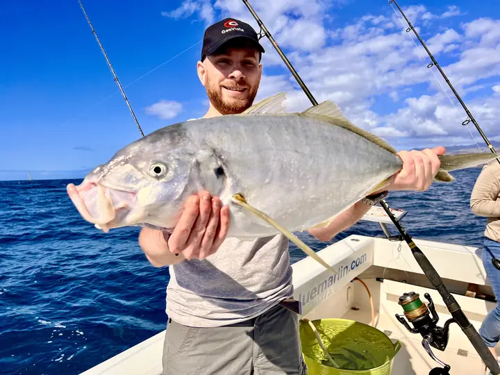 Fiskare med en stor taggmakrill mot den blå himlen