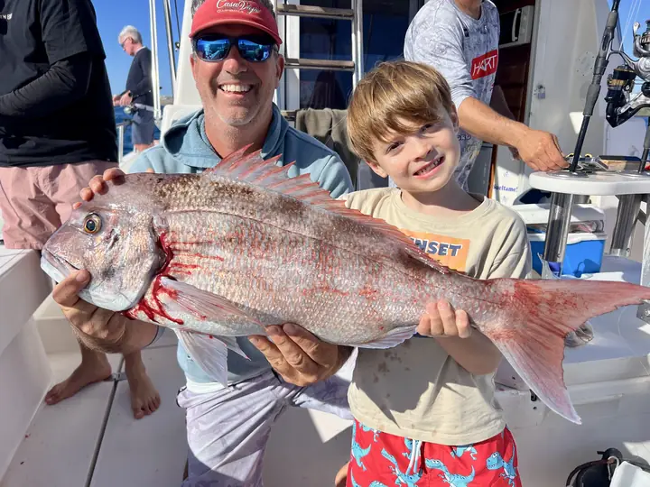 Pappa och son med en röd snapper